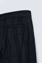 Pantalón de corte recto, color azul marino, confeccionado en tejido jacquard con textura de rayas verticales en relieve. Presenta cierre frontal con botón y bolsillos laterales y traseros de vivo.