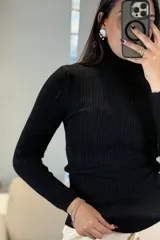 Buzo tipo polera de tejido morley color negro, con cuello alto y mangas largas, de calce ajustado al cuerpo.