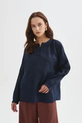Blusa azul marino de viscosa, con cuello mao, escote con botones y frunces. Presenta mangas largas holgadas y detalles bordados al tono en el frente.