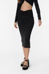 Falda midi negra de corte ajustado, con detalle drapeado y abertura lateral.