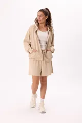 Conjunto de dos piezas compuesto por un buzo con capucha, cierre frontal y bolsillos, y un short con cintura elástica y cordón ajustable. Ambas prendas presentan un diseño holgado y cómodo.