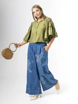 Pantalón wide leg de denim azul, con cintura elástica y apliques de flores grandes en tela vaquera en las piernas.