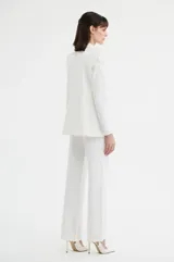 Saco sastrero blanco de doble botonadura, con solapas de muesca y bolsillos con solapa en los laterales. Presenta detalles bordados en las mangas.