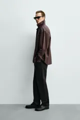Sobrecamisa relaxed fit de cuero color marrón oscuro, con cuello solapa, manga larga con puño abotonado, bolsillo de parche en el pecho y cierre frontal de botonadura.
