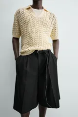 Polo de punto con estructura calada en color beige, confeccionado en algodón. Presenta un calce relajado, manga corta, cuello solapa con abertura frontal y terminaciones acanaladas.