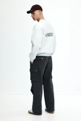 Pantalón cargo gris oscuro de corte holgado, con cintura elástica y bolsillos laterales, traseros y tipo cargo con solapa y botón a presión.