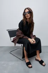 Vestido midi negro de algodón con calce relajado, silueta recta, cuello redondo, mangas cortas amplias y tajos laterales.