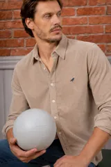 Camisa azul marino de pana, de corte slim fit, con cuello clásico, botones delanteros claros y detalle de ave bordada en el pecho.