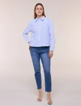 Camisa de algodón celeste con patrón de milrayas finas y aplicaciones florales en relieve deshilachado en el frente. Cuenta con cuello camisero tradicional, cierre frontal con botones, mangas largas con puños abotonados y corte semi holgado.