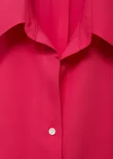 Camisa sin mangas de lyocell color fucsia, con cuello camisero y cierre frontal de botones.