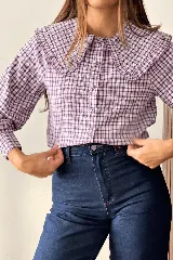 Camisa de manga larga con estampa a cuadros en tonos violeta y blanco, con cuello babero amplio con volados y cierre frontal abotonado.