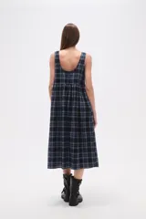 Vestido midi sin mangas confeccionado en algodón con estampado de cuadros en tonos azul y negro. Presenta un diseño holgado con cuello redondo y cierre posterior.