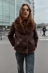 Cazadora reversible de corte recto, con cuello de solapa, manga larga y cierre frontal con botones. Presenta un exterior efecto ante y un interior con acabado de pelo sintético, incluyendo detalles de pelo en los bordes.