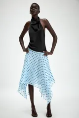 Falda midi de tiro medio color celeste con estampado de lunares negros, diseño asimétrico y forro interior. Cuenta con cierre lateral de cremallera oculta.