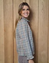 Camisa de manga larga con estampado de rayas verticales en tonos blanco y lila. Presenta cuello alto con volados, cierre frontal con doble botonadura y puños con volados.