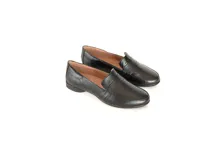 Mocasín de cuero negro con textura sutil, diseño clásico de estilo penny loafer con suela plana y tacón bajo.