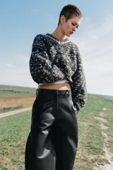 Pantalón de tiro alto con diseño de pierna ancha, confeccionado en tejido efecto piel. Cuenta con bolsillos delanteros, falsos bolsillos traseros de vivo y cierre frontal con cremallera y ganchos metálicos.