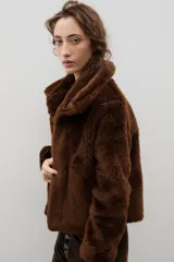 Campera corta de piel sintética en color crema, con cuello amplio tipo solapa y cierre frontal.