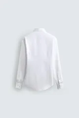 Camisa de corte regular fit confeccionada en tejido de algodón con textura. Presenta cuello italiano, manga larga con puños abotonados y cierre frontal de botones.