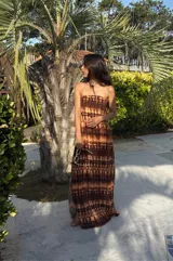 Vestido largo strapless, ajustado al cuerpo, con estampado batik en tonos marrones y naranjas.