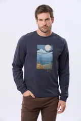 Remera de manga larga en color azul oscuro, con cuello redondo y estampado frontal de paisaje montañoso. Presenta un pequeño parche decorativo en la manga.