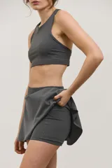 Pollera deportiva corta con calza incorporada, diseñada para actividades como pádel o tenis. Cuenta con cintura ancha de ajuste cómodo y bolsillo invertido en la calza para guardar pelotas. Confeccionada en tejido liviano y elastizado.