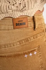 Jean de tiro alto con corte wide leg y acabado lavado en tono camel. Presenta diseño de cinco bolsillos, cierre frontal con botón y cremallera, y bajo con terminación al corte.