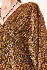 Vestido corto de mangas largas abullonadas con puños elásticos, escote en V profundo y corte holgado. Presenta un estampado animal print abstracto en tonos marrones y negros.