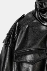 Cazadora de estilo bomber en efecto piel color negro, con cuello subido, manga larga y bajo elástico. Presenta trabillas en los hombros, bolsillos frontales con solapa y cierre de cremallera con botones a presión ocultos.