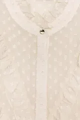 Camisa de cuello redondo y manga larga con puños. Presenta un diseño semitransparente con textura de pequeños puntos en relieve y volantes decorativos en el frente. Cierre frontal con botones ocultos.