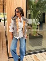 Chaleco de piel sintética en color gris, con diseño reversible. El interior presenta un forro de tela color mostaza con estampado floral bordado. Posee un corte holgado y sin mangas.