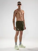 Short de baño verde militar con bordado de una sirena blanca en la pierna izquierda. Tiene calce sastrero, cintura elástica con cordón ajustable, bolsillos laterales y bolsillo trasero con cierre. Incluye suspensor de malla fina hipoalergénico.