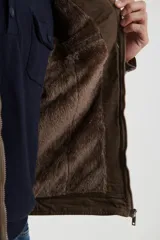 Campera técnica de tejido elástico en color azul marino, con capucha ajustable, cierre frontal y bolsillos laterales con cierre. Cuenta con forro interior de micro polar y ajuste en el ruedo.