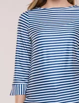 Remera de agua de silueta estilizada confeccionada en tejido técnico elastizado con protección solar UPF 50, con escote barco amplio y mangas 3/4 terminadas con puño en rayas verticales a contraste con pequeña abertura. Presenta aberturas laterales en el bajo decoradas con botones dorados grabados y ruedo recto de calce cómodo.