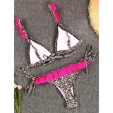 Bikini de dos piezas con estampado animal print. El top es de estilo triángulo con breteles decorados con volados fucsias. La bombacha es tipo tanga con laterales atados y un detalle de volado fucsia en la parte frontal.