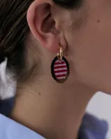 Dije para aros con forma ovalada, borde metálico dorado festoneado y centro de resina con estampado de cuadros en tonos marrón y lila.