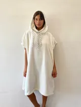 Salida de mar de toalla color crudo, con diseño holgado, capucha integrada y cordones ajustables en el cuello.