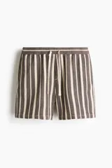 Short de corte regular fit en tejido texturizado con mezcla de algodón, con diseño de rayas verticales en tonos marrón y crudo. Cuenta con cintura elástica ajustable con cordón y bolsillos laterales.