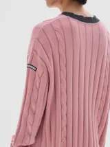 Buzo tejido de ochos color rosado, con cuello a la base y rayas contratono en puños y cuello.