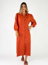Vestido camisero largo de color naranja, con mangas largas abullonadas y cierre frontal de botones.