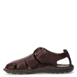 Sandalias de cuero marrón con diseño cerrado en la puntera y aberturas laterales. Posee ajuste con velcro en el talón y suela de goma con costuras visibles.