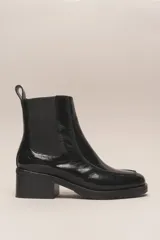 Bota Chelsea de cuero charol negro, con elástico lateral, punta cuadrada y taco bajo.