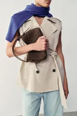 Mini bolso de mano de color marrón con diseño trenzado y doble asa de mano. Incluye función bandolera con correa extraíble, forro interior y cierre mediante botón imantado.