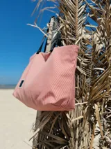 Bolso tipo tote rayado en tonos rosa y blanco, con asas cortas negras y correa larga regulable negra.