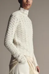 Jersey de punto con cuello subido y manga larga, confeccionado con un diseño de tejido combinado que presenta una textura calada y delicada.