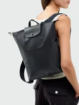Mochila Longchamp modelo Le Pliage, color negro, confeccionada en nylon resistente con solapa y asa superior de cuero granulado. Presenta cierre de cremallera con tirador metálico y correas ajustables.