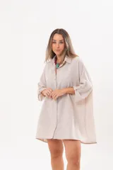 Vestido camisero beige de lino, con escote en V, cuello clásico, mangas tres cuartos regulables y cierre frontal de botones.