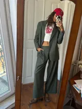 Blazer de sastrería con diseño oversize y hombreras pronunciadas. Presenta un estampado de rayas verticales finas, cierre frontal con botones nacarados y forrería a contratono. Incluye una etiqueta bordada decorativa en la manga.