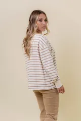 Buzo liviano de manga larga con diseño de rayas horizontales en color beige y blanco. Presenta un cuello redondo con cartera frontal de botones tipo henley, hombros caídos y calce holgado con puños acanalados.