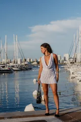 Vestido corto blanco de encaje con escote drapeado profundo y sin mangas.